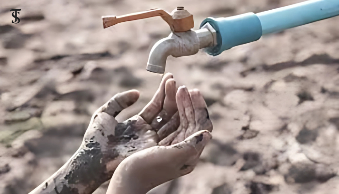 A child’s muddy hands reaching out to an empty water tap, symbolizing the struggle and urgency of the global water crisis.